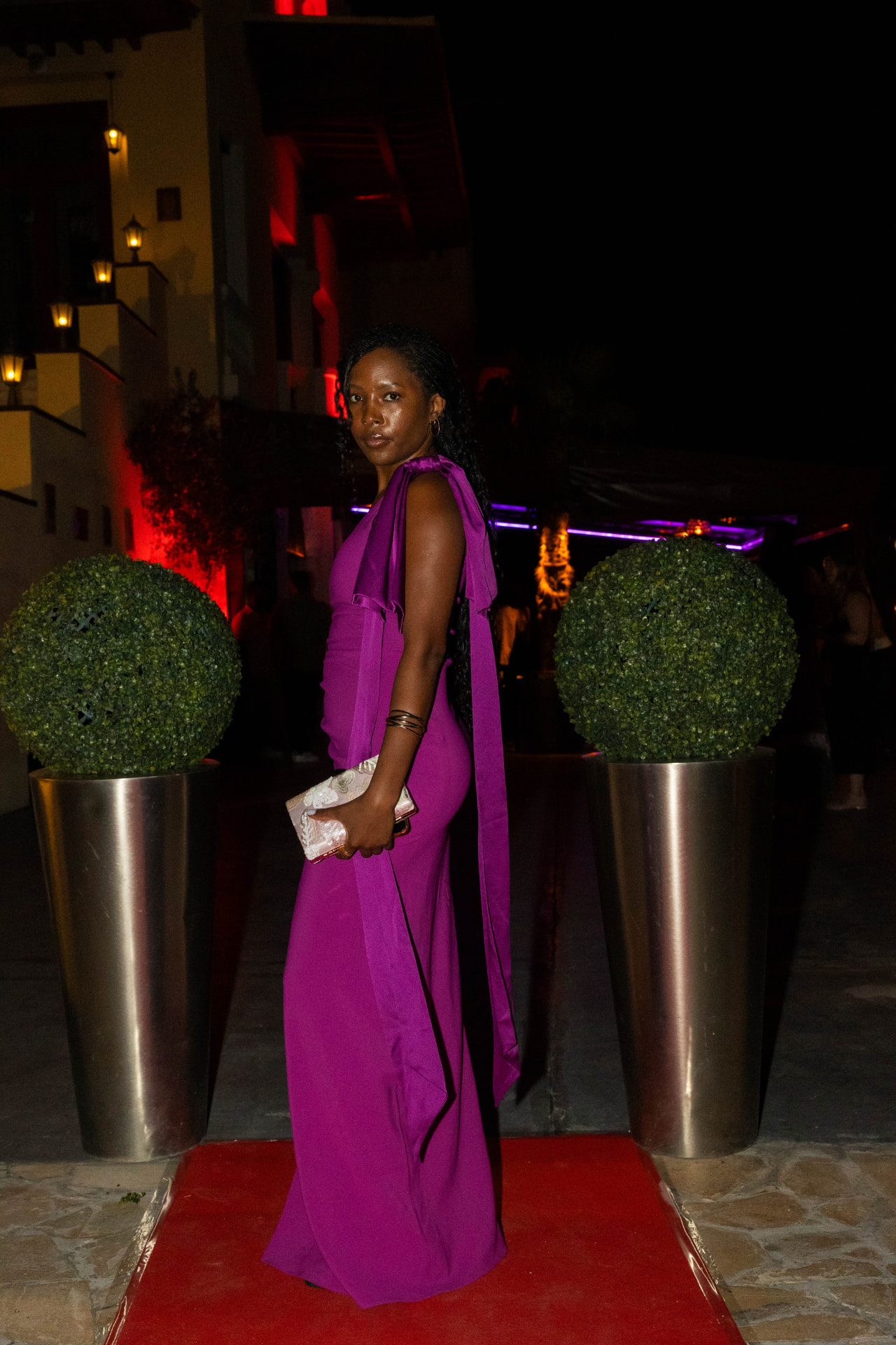 Guest in a fuchsia dress arriving on the red carpet at an African Society night